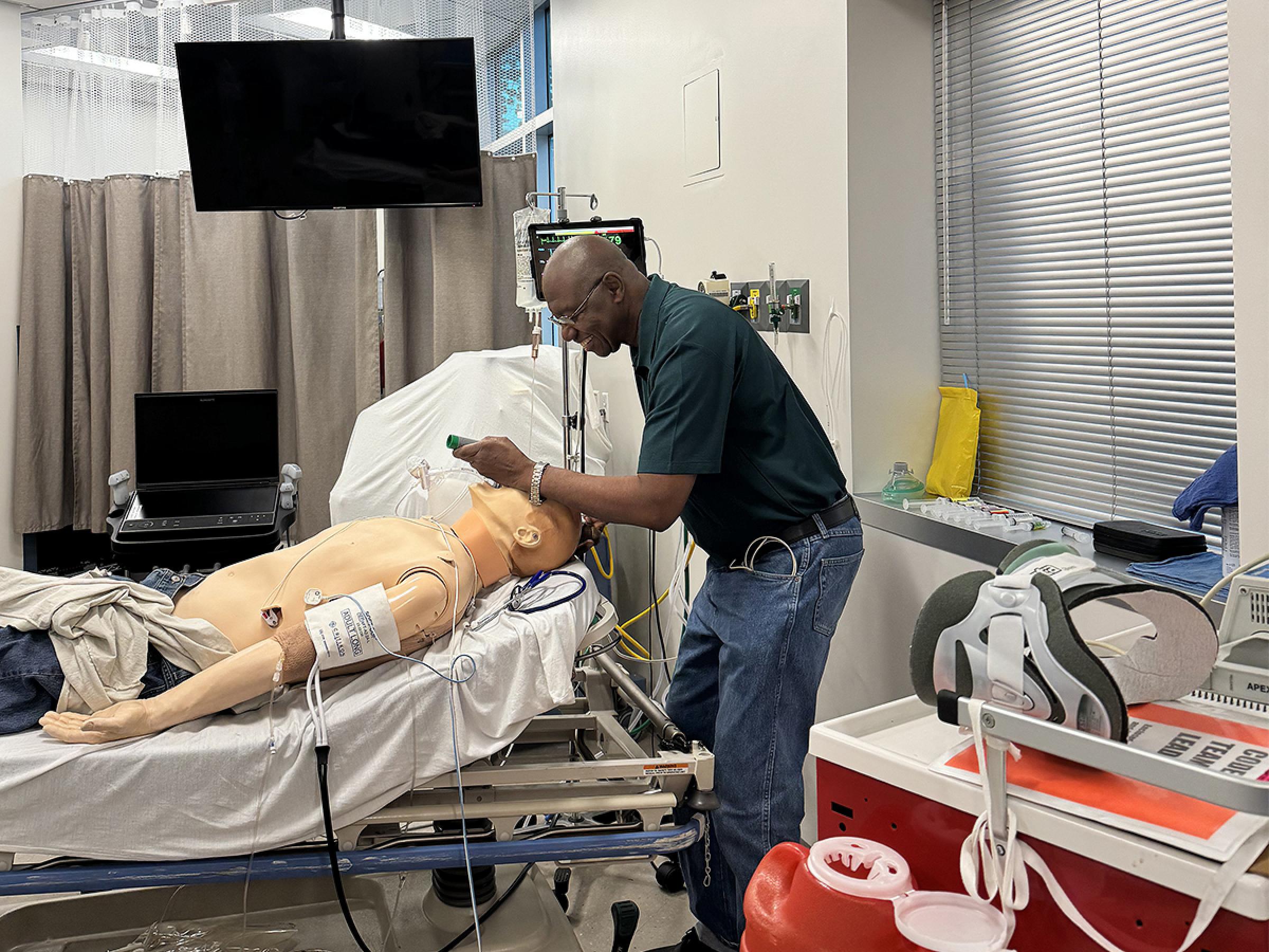 Professor Baro in the Center for Patient Simulation using a laryngoscope on a mannequin.