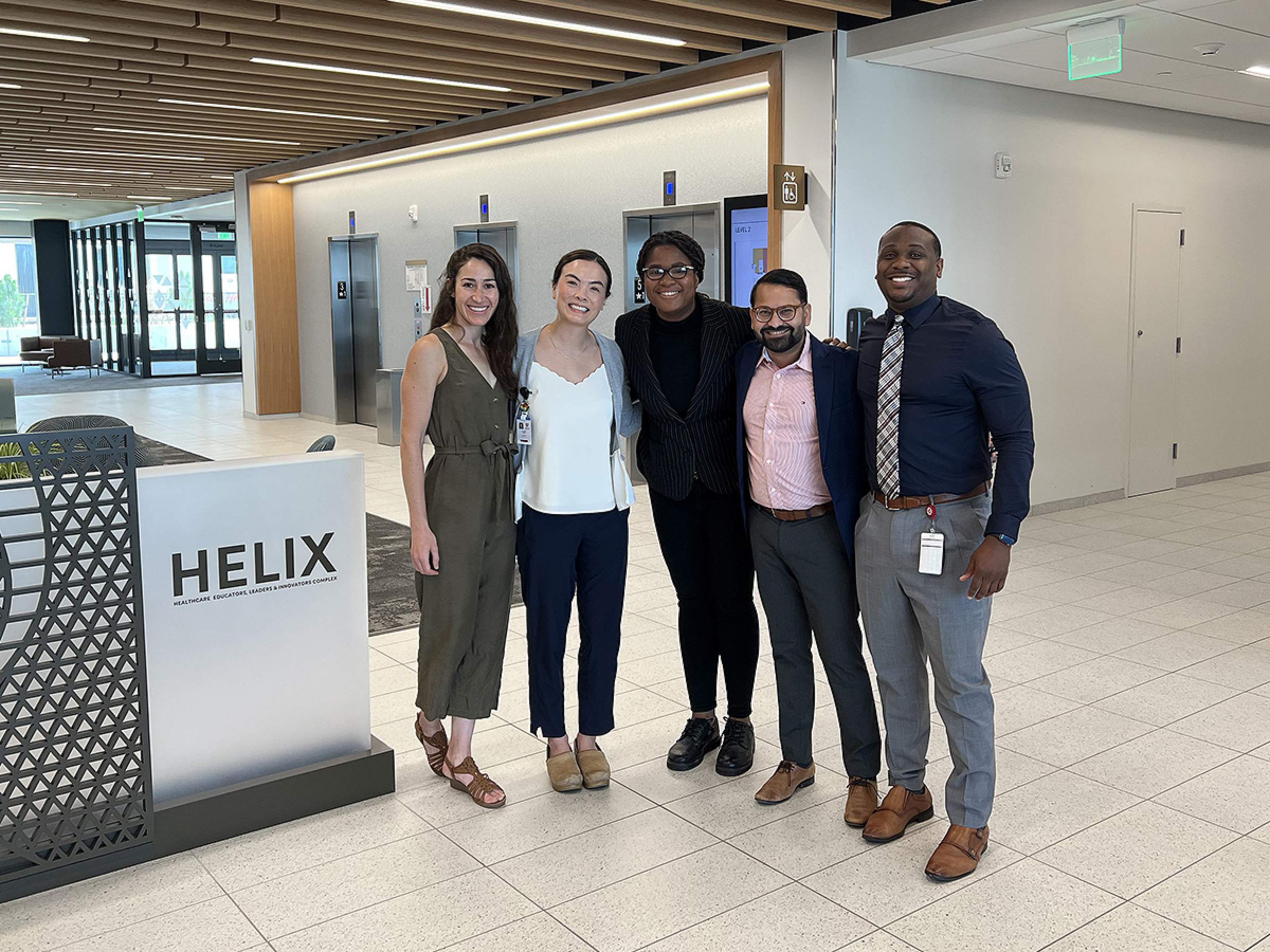 Five people standing together for a photo inside the entrance to the HELIX building.