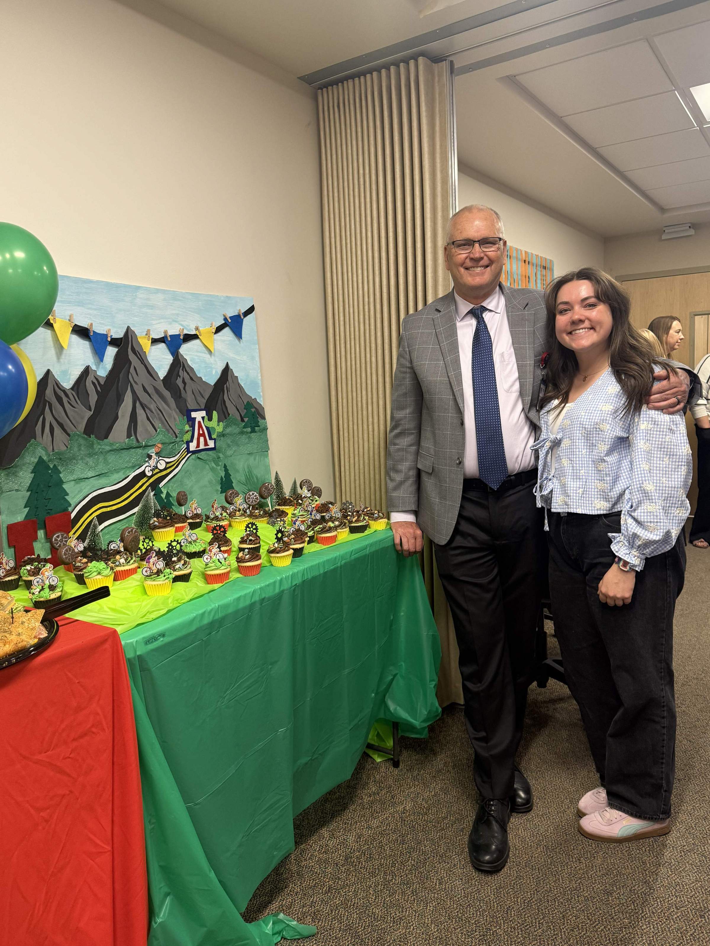Dr. Ken Johnson poses with his daughter next to a cupcake display.