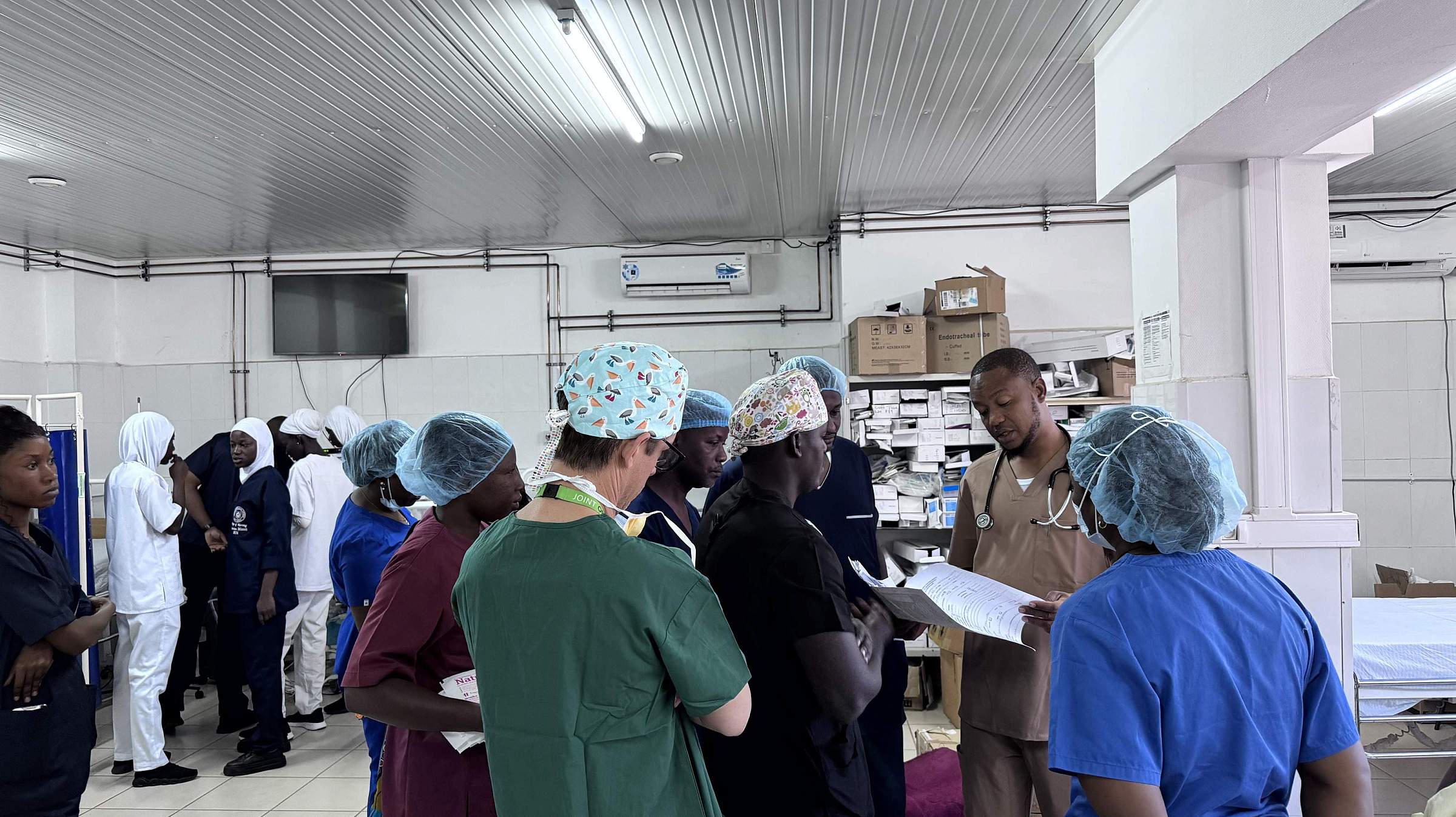 Doctors and nurse anesthesiologists gather in scrubs and protective gear.